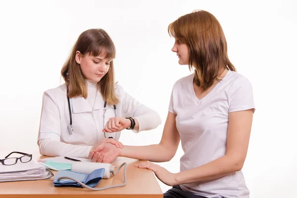 Médico en la mesa comprueba el pulso de un paciente — Foto de Stock