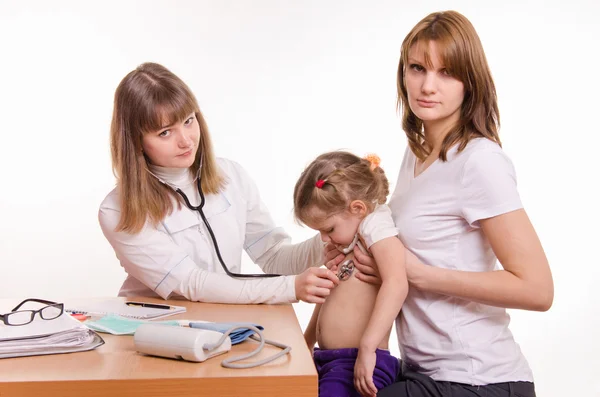 Pediatra examinando uma criança nos braços da mãe — Fotografia de Stock