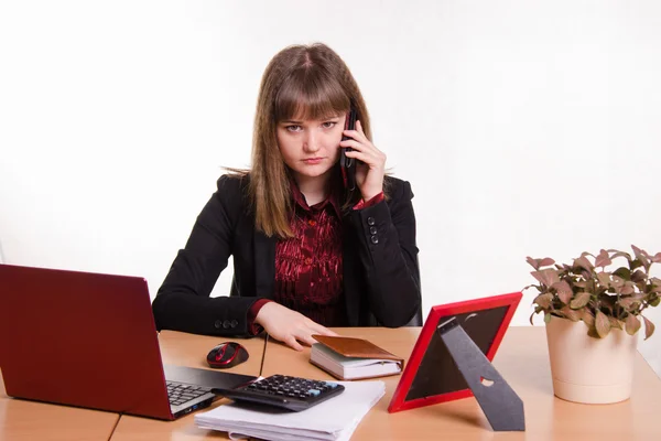 La chica detrás de la mesa de la oficina habla por teléfono — Foto de Stock