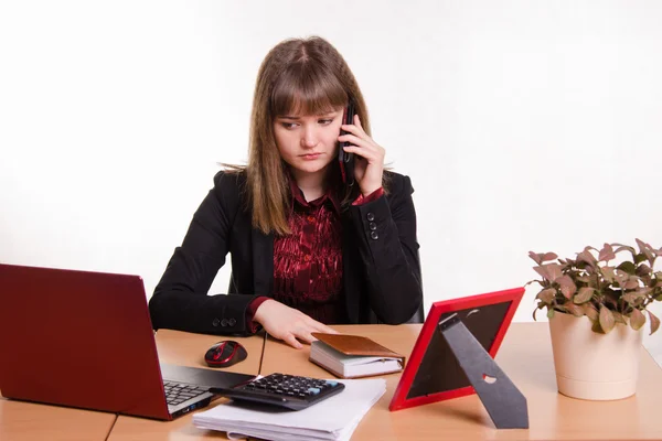 Flickan bakom skrivbord på telefon lyssnar till en vän — Stockfoto