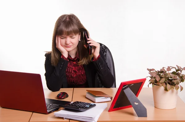 Girl behind office desk listening to cry of the phone — Stock Photo, Image