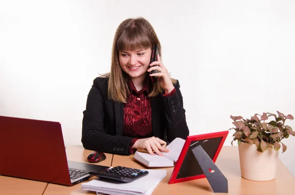 Het meisje achter bureau praten over telefoon Stockafbeelding