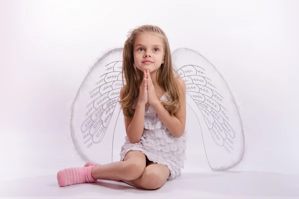Fille assise avec des ailes d'ange mains pliées — Photo