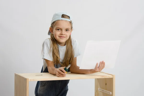 Girl-collector of furniture with a screwdriver and drawing collects furniture — Stock Photo, Image