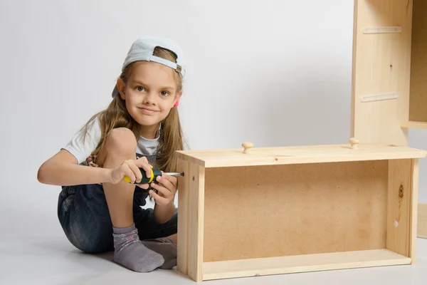 Dziewczynka w kombinezon kolektor zbiera meble szufladzie kredensu — Zdjęcie stockowe