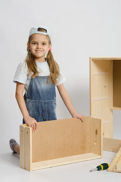 Girl collects furniture — Stock Photo, Image