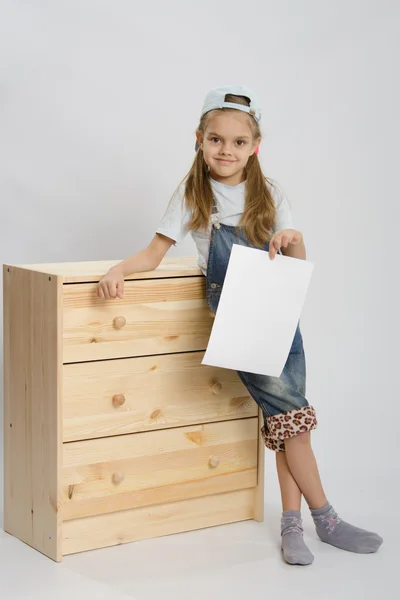 Muchacha en overoles muebles de colección cerca del pecho con una hoja de papel —  Fotos de Stock