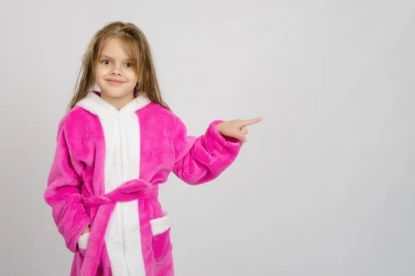 Zes jaar oud meisje in badjas wijzend op lege ruimte — Stockfoto