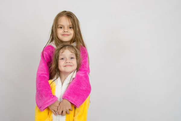 Chica en albornoz abrazando a su hermana una bata de baño — Foto de Stock