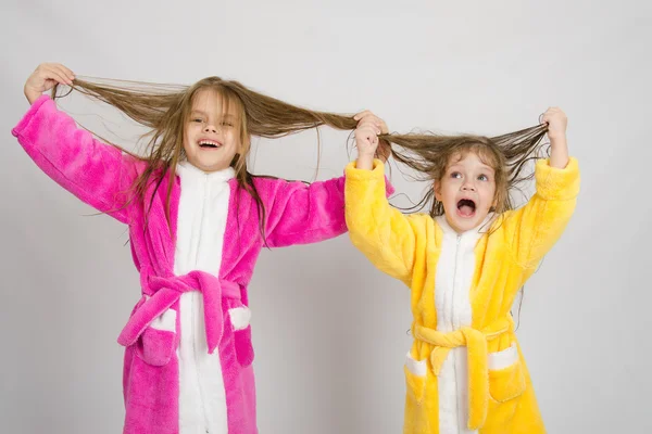 Две девушки веселятся в халатах держат влажные волосы — стоковое фото