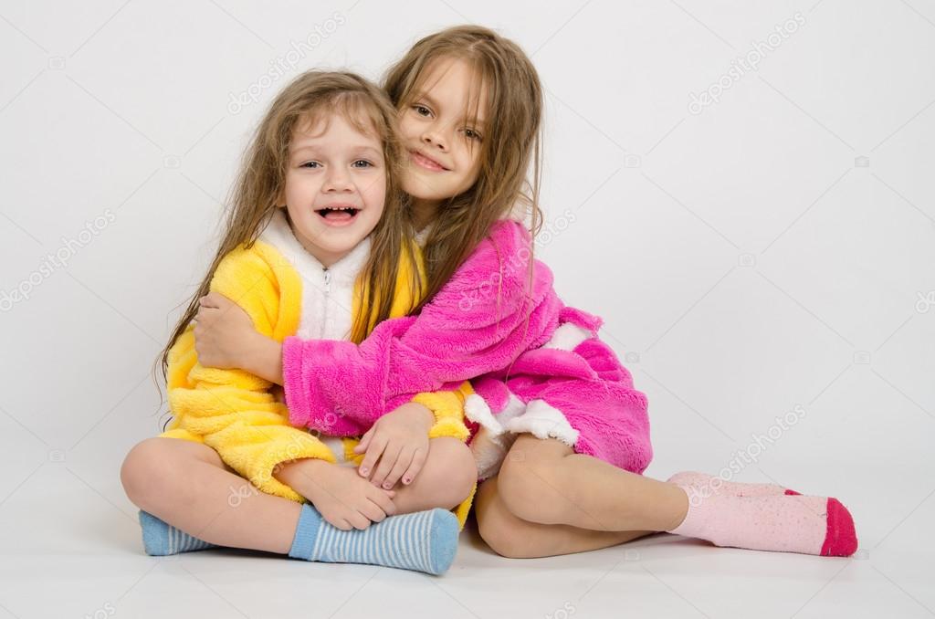 Two girls sit in robes