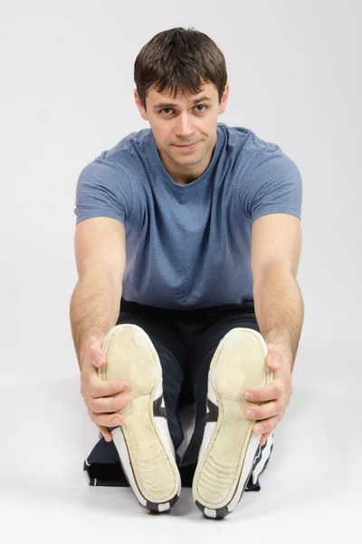 Den unge mannen sträcker sig musklerna i benen — Stockfoto