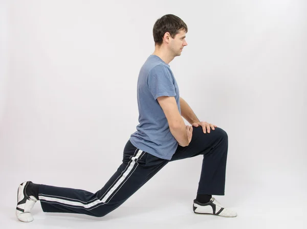 Idrottaren utför stretching med knäböj — Stockfoto