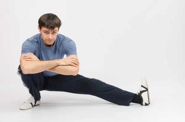 Esportista agachamento músculos puxando o pé esquerdo — Fotografia de Stock