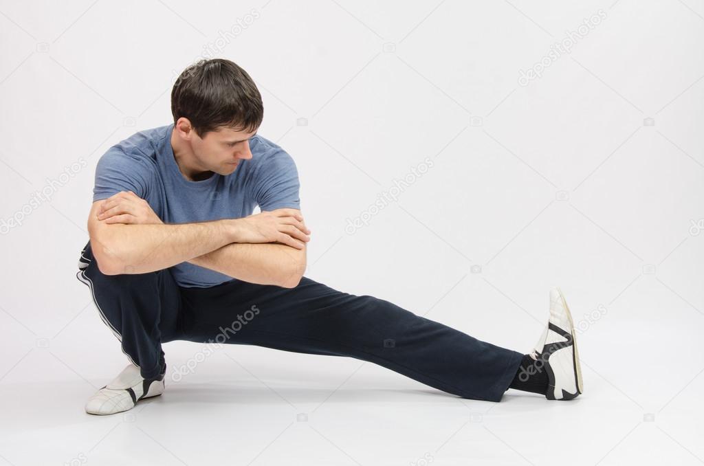 Athlete crouching stretches muscles of left leg