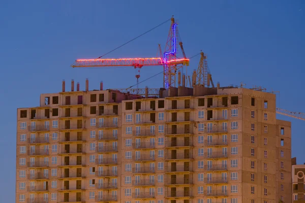 Kijk na zonsondergang op het onvoltooide huis met een kraan — Stockfoto