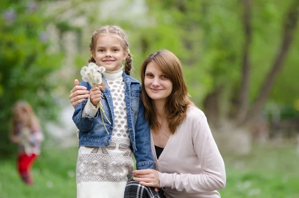 Mladá žena objetí své dcery s pampelišky — Stock fotografie