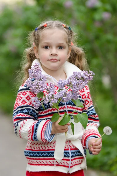 Porträtt av flicka med syrener och maskrosor i händerna — Stockfoto