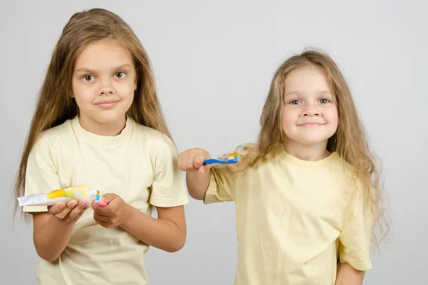 The girl squeezes out a tube of toothpaste on the brush — Stock Photo, Image