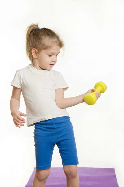 Four-year girl is engaged in raising the dumbbell exercise — Stock Photo, Image