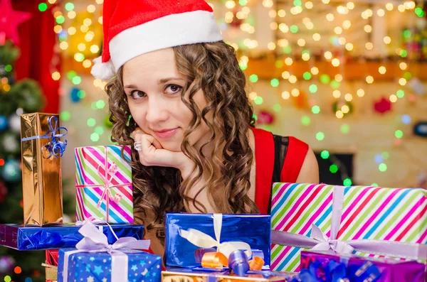 Schönes Mädchen an einem Tisch mit Weihnachtsgeschenken — Stockfoto