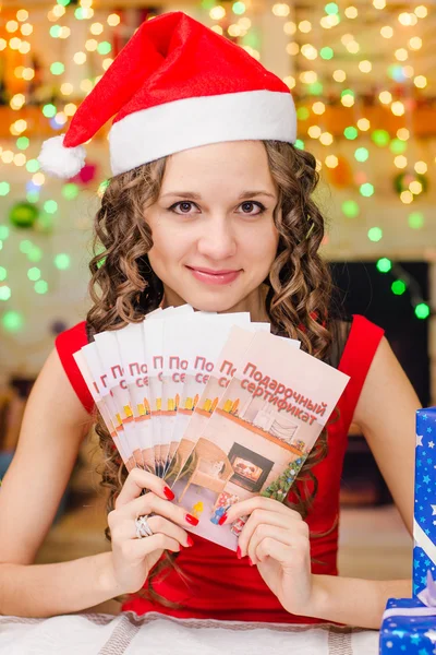 The girl is holding a Christmas gift certificates — Stockfoto