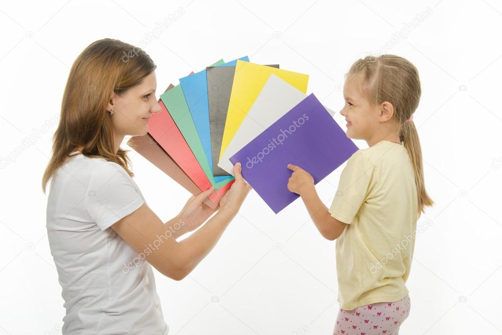 child shows colors the image in hands of women