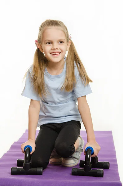 Sechsjähriges Mädchen auf einem Teppich mit Haltestellen für Liegestütze — Stockfoto