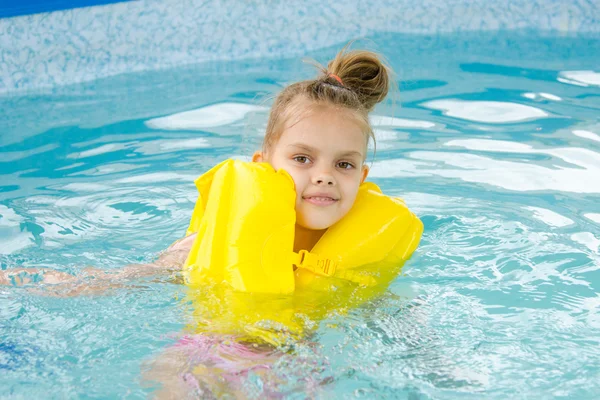 Ragazza che nuota in piscina con il giubbotto di salvataggio — Foto Stock