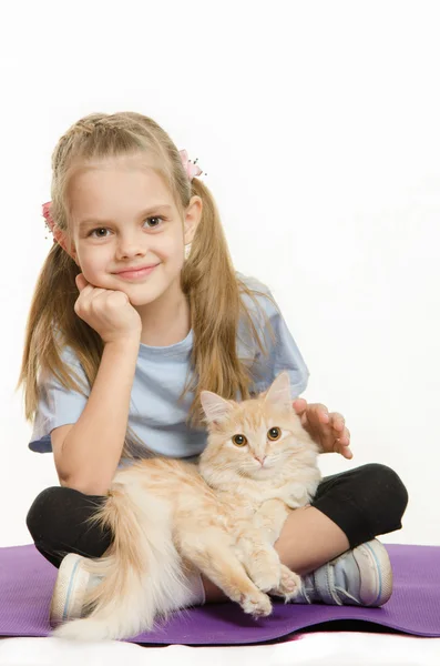 Šest let stará dívka sportovec sedí na koberci s kočkou na klíně — Stock fotografie
