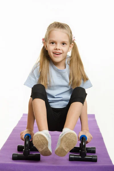 Six year old girl on a rug engaged with stops for push-ups — Stock Photo, Image