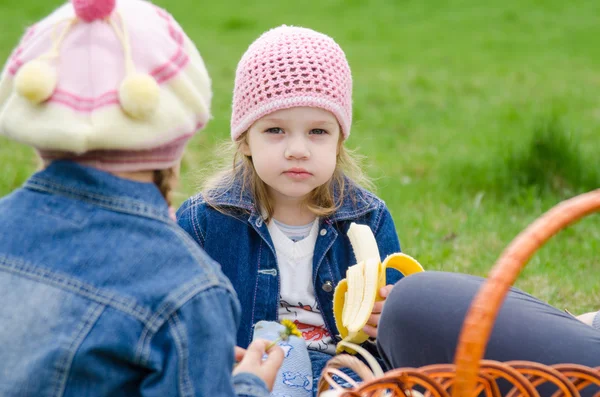 Ledsna flickan på en picknick äter banan — Stockfoto