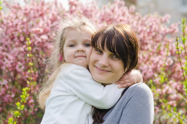 Embraces of mother and daughter on spring background — Stock Photo, Image