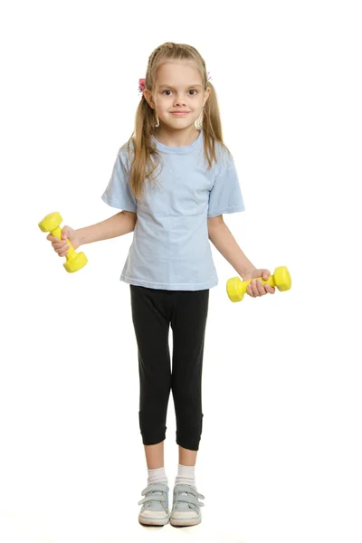 Six year old girl athlete engaged in exercise with dumbbells — Stock Photo, Image