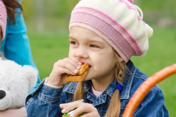 Girl eating cake at a picnic — Stock Photo, Image