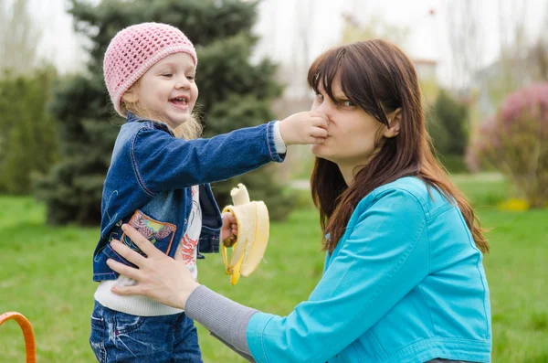 Chica con plátano madre pellizcado nariz —  Fotos de Stock