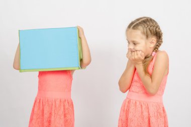 The girl was frightened other girl with a box on his head clipart