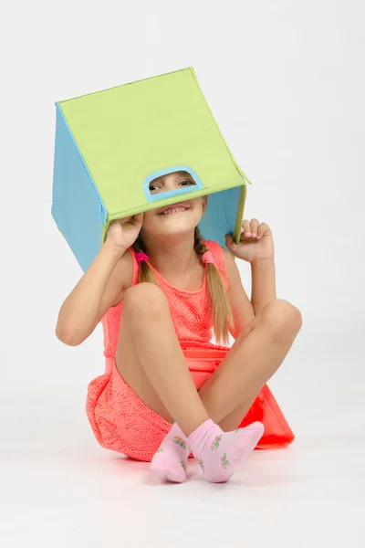 Девушка балуется в коробке для игрушек положить на голову — стоковое фото