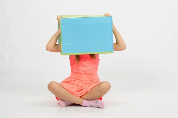 Девушка сидит на полу с коробкой на голове — стоковое фото