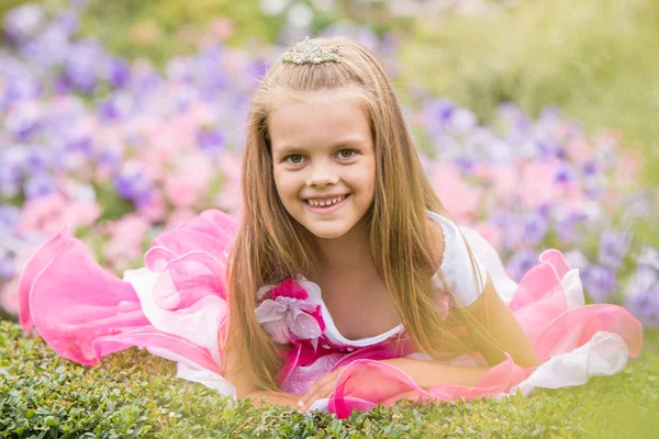 Princesa menina em um vestido bonito em uma cama de flores — Fotografia de Stock