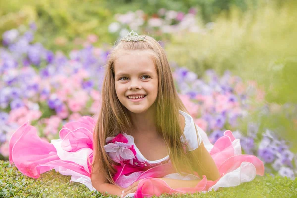 Five-year girl in a beautiful dress in a bed of flowers — Stock Photo, Image