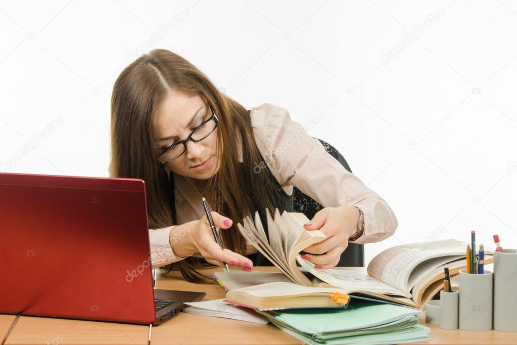 Teacher leafing through a book to find information