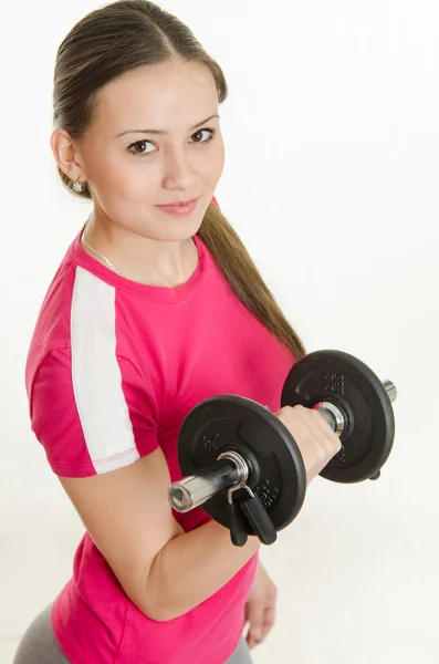 Girl athlete looking up holding a dumbbell in her hand — Stock Photo, Image