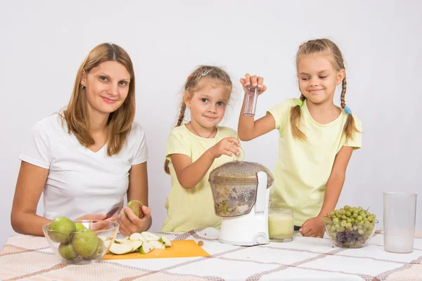 Família feliz prepara suco espremido na hora em um espremedor — Fotografia de Stock