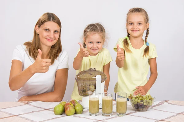 母亲和两个女儿表明竖起大拇指的准备新鲜榨果汁 — 图库照片