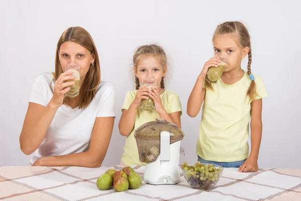 Madre y dos hijas bebiendo jugo recién hecho — Foto de Stock