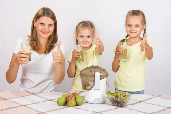 Mother and two daughters show a thumbs up freshly prepared juice — Stock Photo, Image