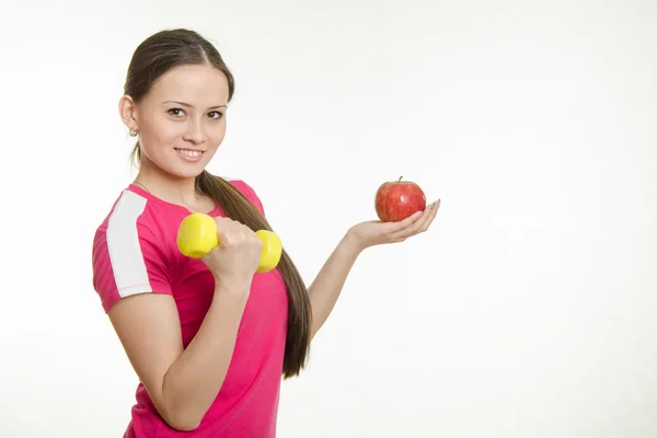 Sportsmenki trzymając hantle w prawej ręce i jabłkiem w lewej ręce — Zdjęcie stockowe