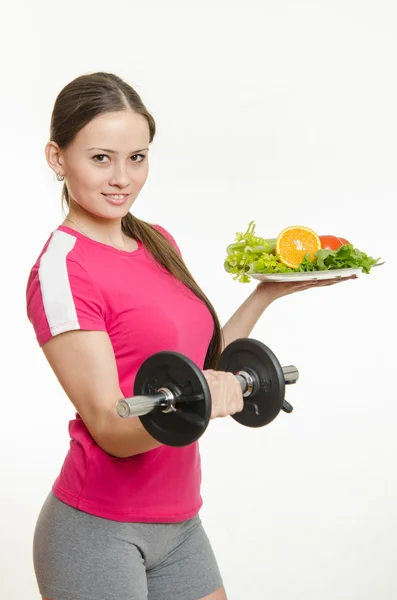 Sportswoman che tiene un manubrio e una ciotola di frutta Foto Stock