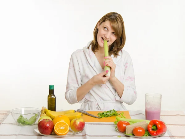 Happy housewife biting celery and looking up — Zdjęcie stockowe